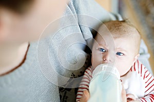 Father feeding newborn baby daughter with milk in nursing bottle