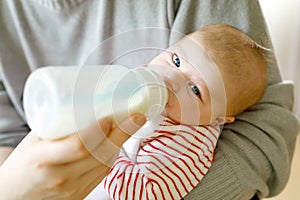 Father feeding newborn baby daughter with milk in nursing bottle