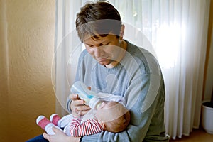 Father feeding newborn baby daughter with milk in nursing bottle