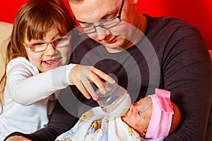 Father feeding newborn baby girl with milk bottle