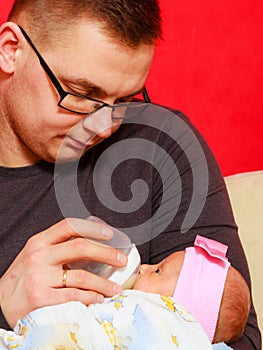 Father feeding newborn baby girl with milk bottle