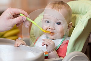 Father feeding small baby with spoon