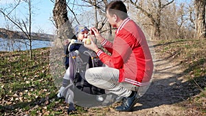 Father feeds the kid with a spoon while walking outdoors