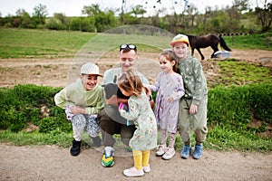 Father with four kids on an animal eco farm hold baby sheep lamb in hand