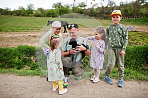 Father with four kids on an animal eco farm hold baby sheep lamb in hand