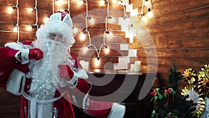 Father Frost Santa Claus dances against the background of a bright garland.