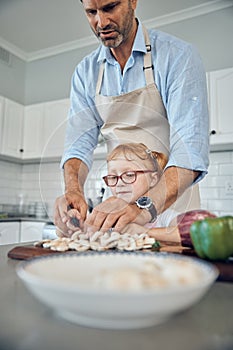 Father, girl in kitchen and cooking food together for healthy, organic family lunch and cutting vegetables at home. Dad