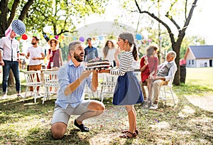 Father giving a cake to a small daughter on a family celebration or a birthday party.