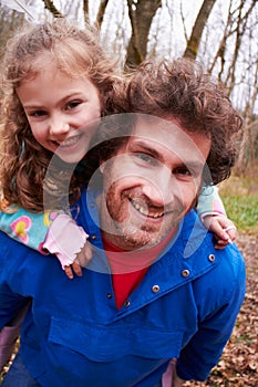 Father Giving Daughter Piggyback Ride On Countryside Walk