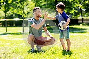 Father giving five to son with soccer ball at park