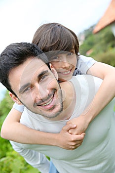 Father giving a piggyback ride to his son outdoors