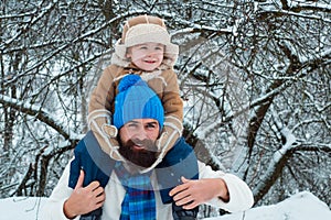 Father giving son ride on back in park. Child sits on the shoulders of his father. Christmas holidays and winter new