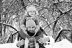 Father giving son ride on back in park. Child sits on the shoulders of his father. Christmas holidays and winter new