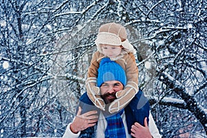 Father giving son ride on back in park. Child sits on the shoulders of his father. Father and son Having Fun in Winter