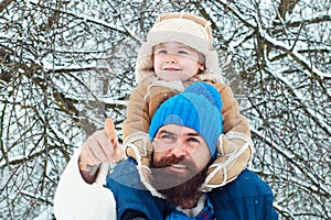 Father giving son ride on back in park. Child sits on the shoulders of his father. Portrait of happy father giving son
