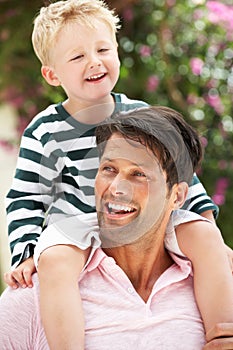 Father Giving Son Ride On Shoulders Outdoors