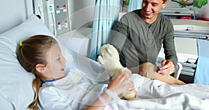 Father giving teddy bear to her sick daughter