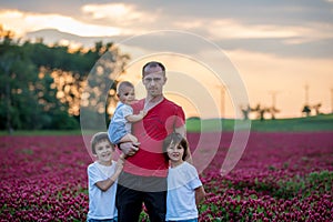 Father, having his portrait with his three sons, boys, in crimson clover field on sunset