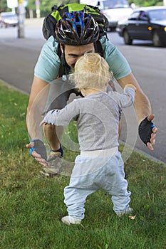 Father hedging their baby, toddler learning to walk