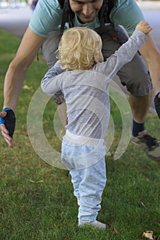 Father hedging their baby, toddler learning to walk