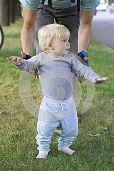 Father hedging their baby, toddler learning to walk