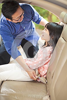 Father help daughter to fasten a seat belt