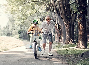 Father help his son learn to ride bicycle