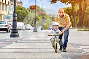 Father help his son ride a bicycle