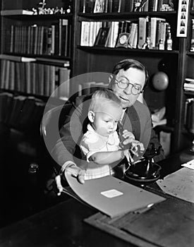 Father helping baby use telephone