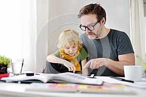 Father helping child do his homework at home. Homeschooling, distance learning, online studying, remote education for kids during