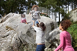 Father Helping Children To Jump Off Rocks