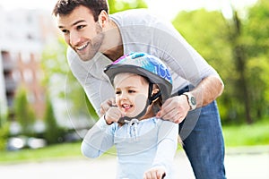 Father helping daughter with bike helmet