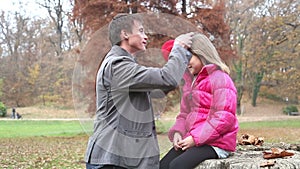 Father helping daughter put on jacket and putting her cap on the head