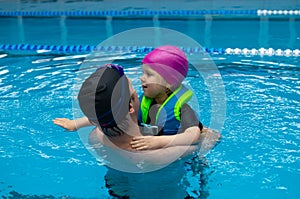 Father helping his little daughter overcome fear of swimming. Young father teaching his fearful daughter how to swim in