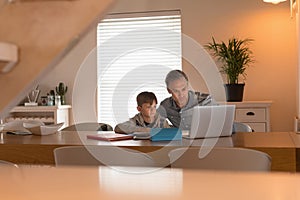 Father helping his son with his homework while using laptop