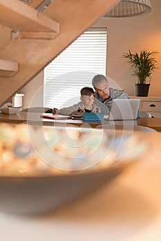 Father helping his son with his homework while using laptop