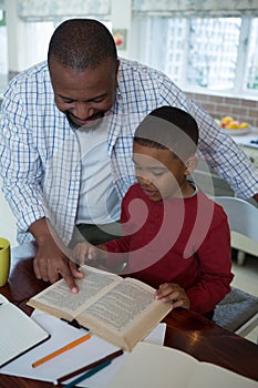 Father helping his son with homework in kitchen