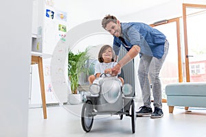 Father helping his son to drive a toy peddle car