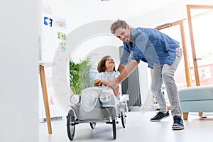 Father helping his son to drive a toy peddle car