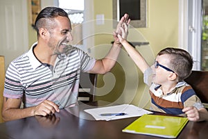 Father helping son do homework. Parent helps his child