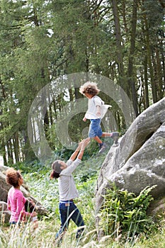 Father Helping Son To Jump Off Rocks