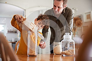 Father Helping Son To Refill Food Containers At Home Using Zero Waste Packaging