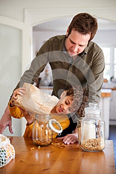 Father Helping Son To Refill Food Containers At Home Using Zero Waste Packaging