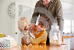 Father Helping Son To Refill Food Containers At Home Using Zero Waste Packaging photo