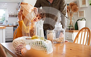 Father Helping Son To Refill Food Containers At Home Using Zero Waste Packaging