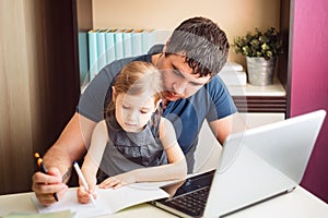 The father helps the daughter to do lessons on distance learning. Online education using a laptop.