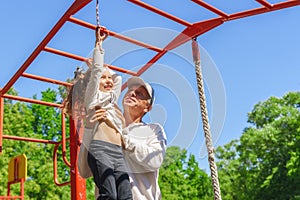 Father helps his child`s daughter to climb the rope. Concept of helping young people