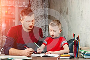 The father helps his son to do homework for the school.