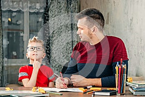 The father helps his son to do homework for the school.