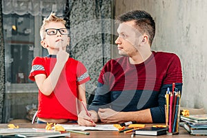 The father helps his son to do homework for the school.